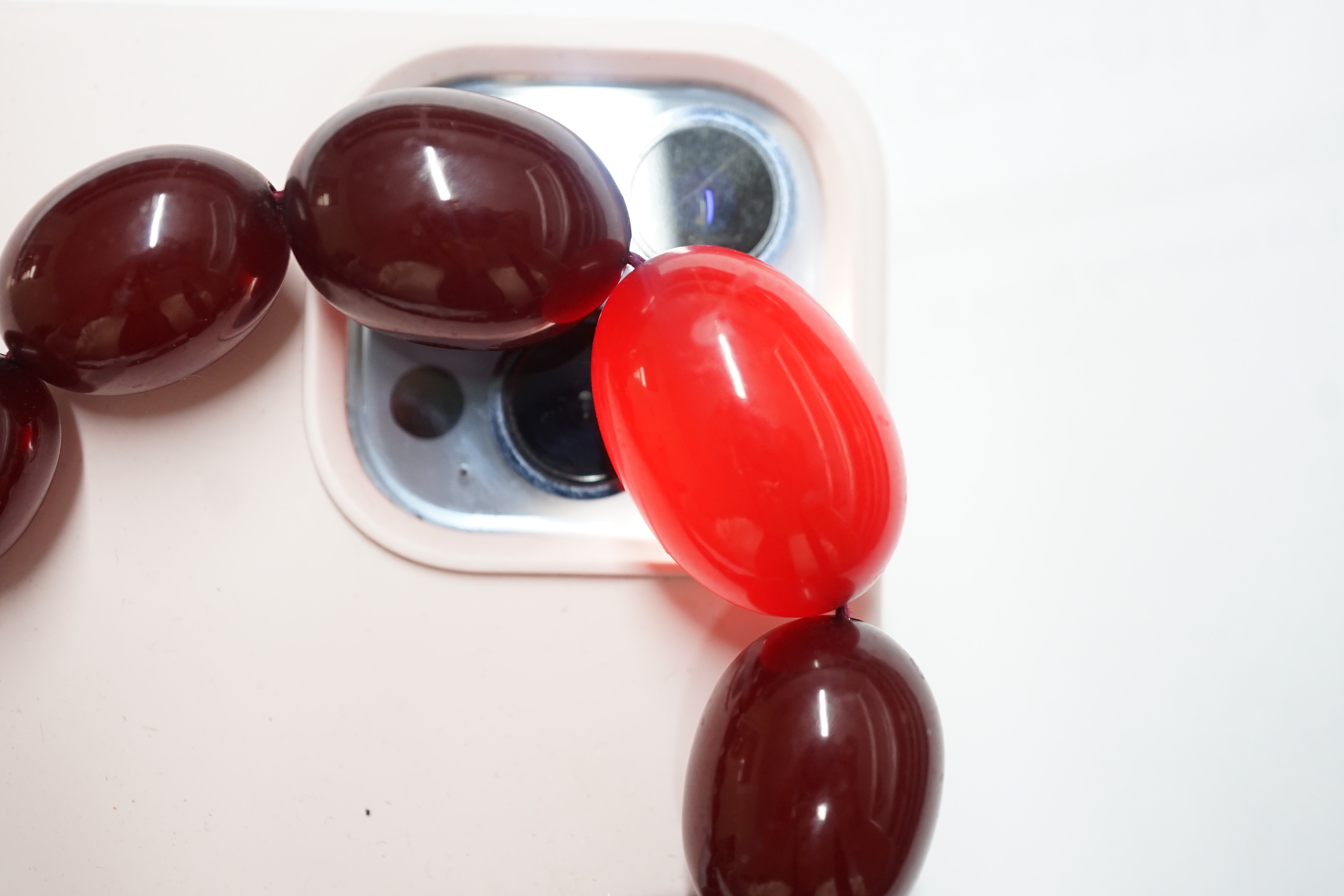 A single strand graduated simulated cherry amber necklace, one other necklace and some loose beads